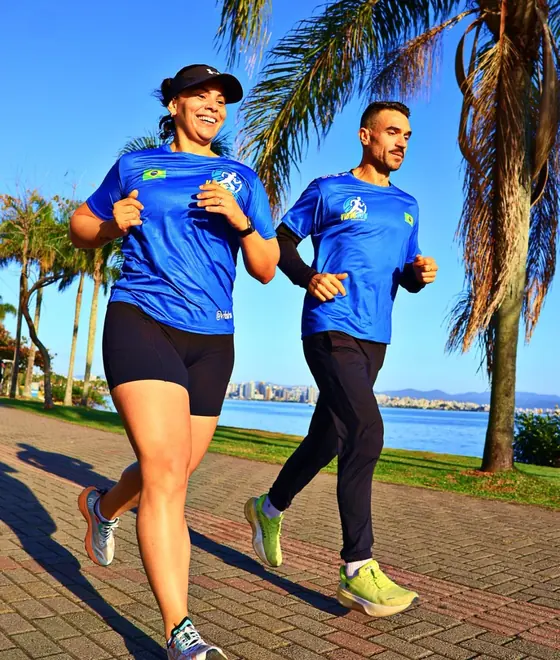 Izaias Vidal correndo lado a lado com uma aluna sorridente na orla da Beira-Mar Norte