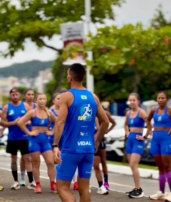 Izaias Vidal, de costas com a regata VIDAL, orientando um grupo de alunas e alunos durante um treino